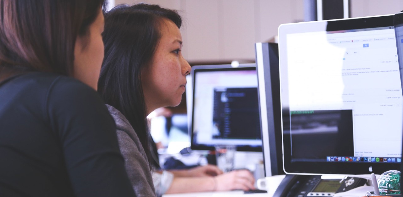 Image of two people in front of a computer at a desk