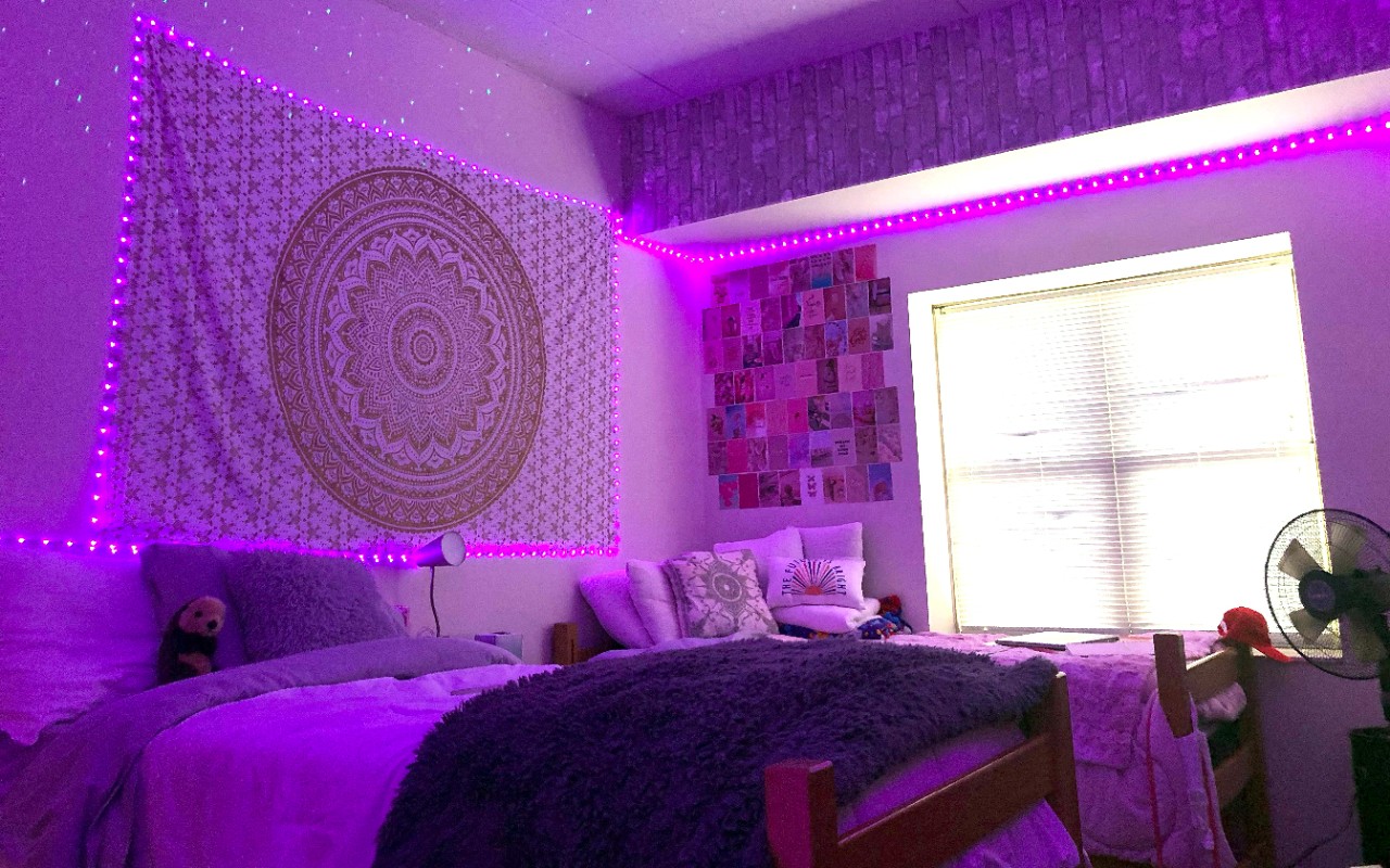 Purple lights surround the room f two beds and wall decorations. 